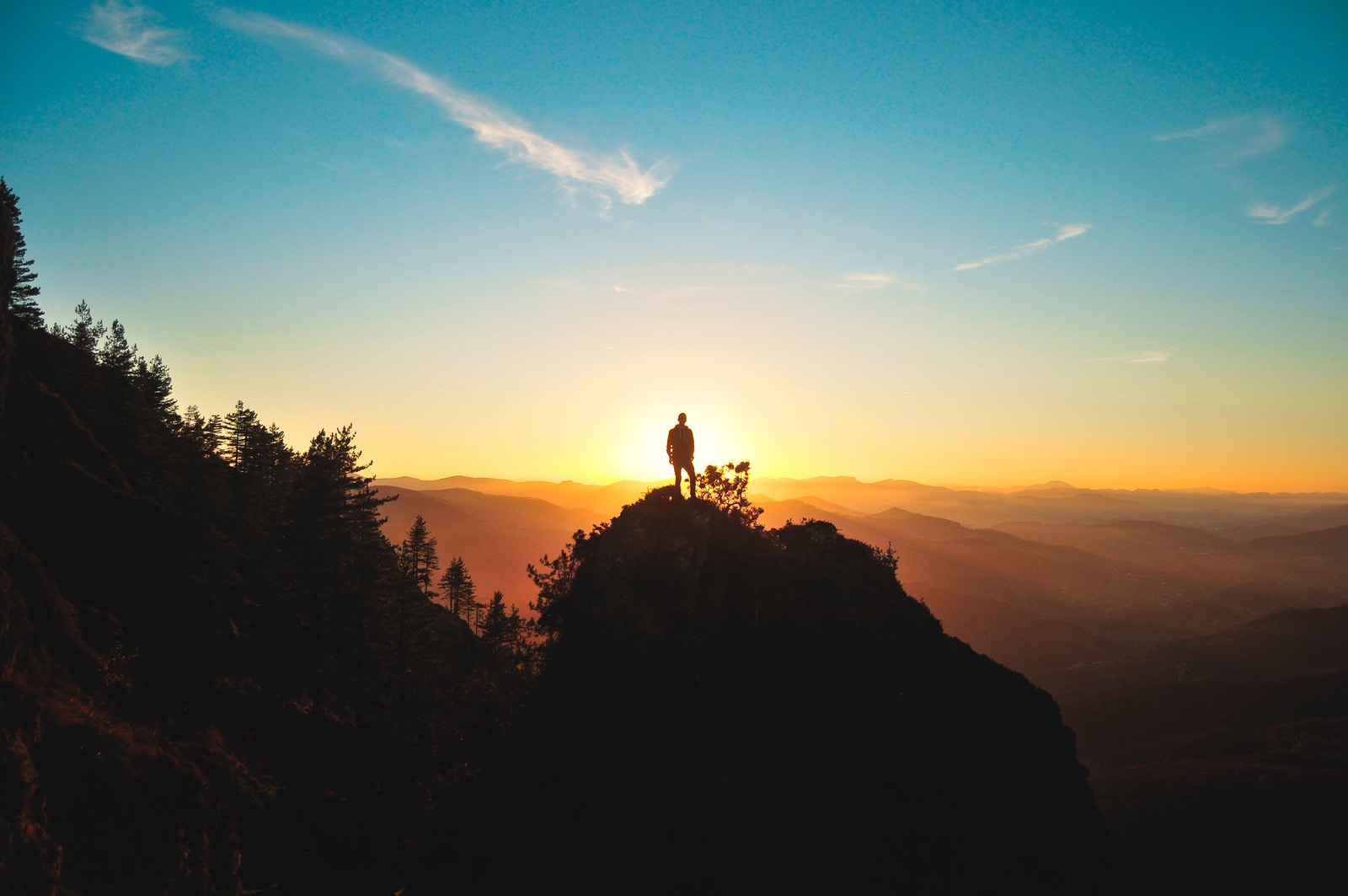 silhouette of man standing on mountain peak