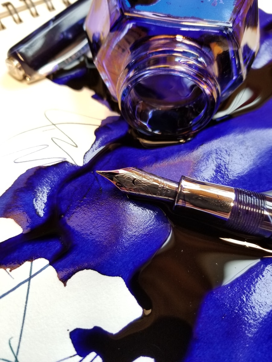 close up photo of spilled blue ink with fountain pen