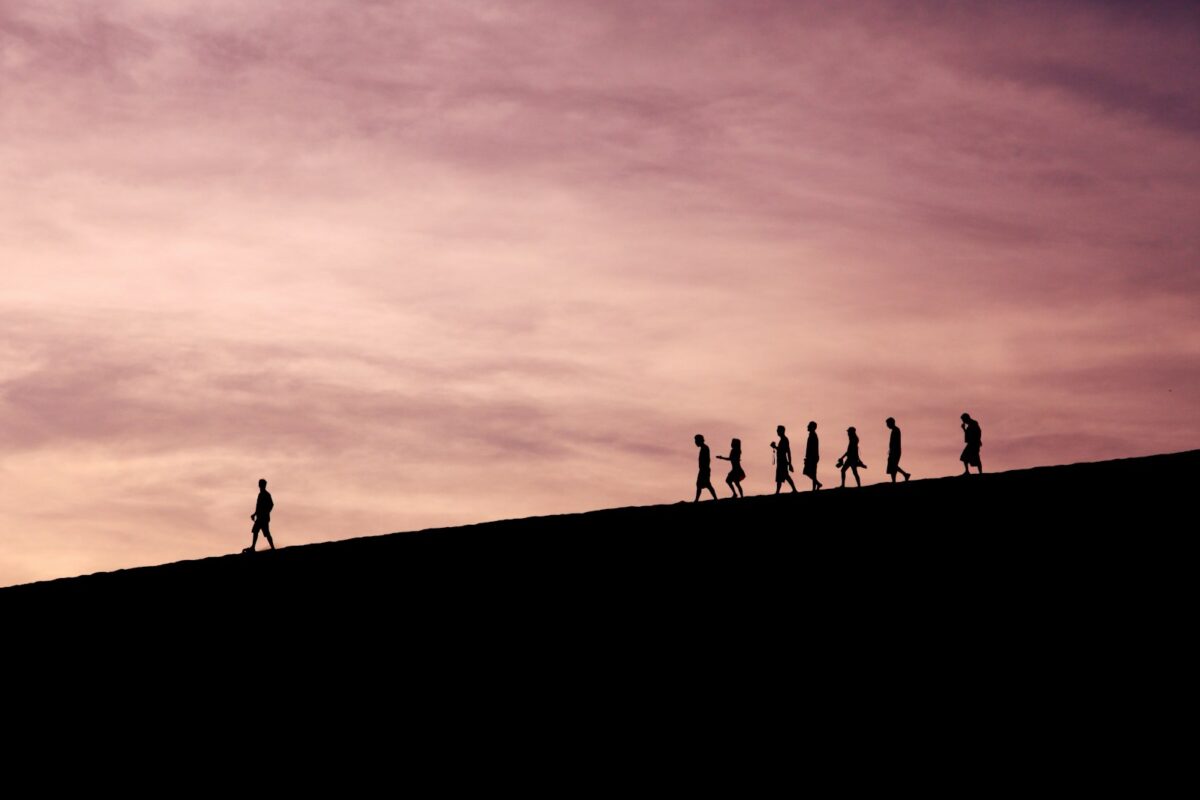 silhouette of people on hill following a leader