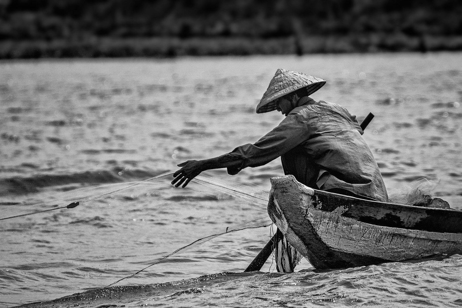 grayscale photo of man in hat and long sleeve shirt sitting on boat on water