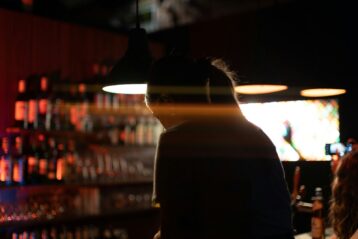 a person wearing a hat in a smoke-filled tavern